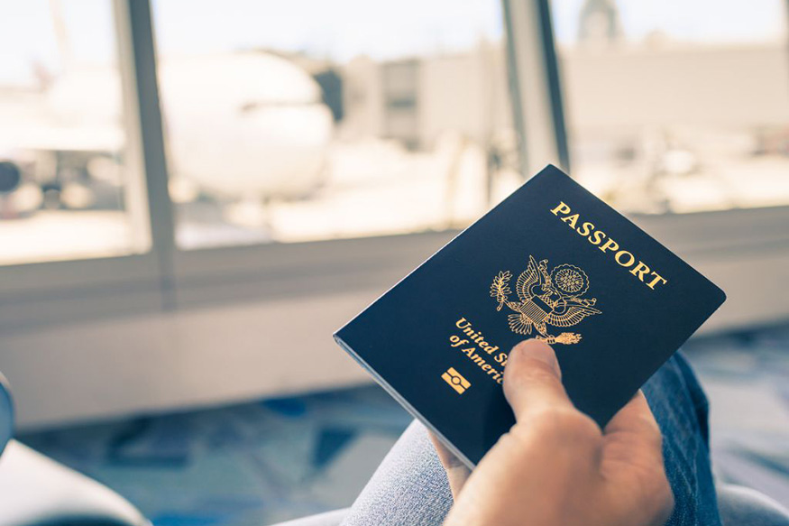 Traveler in an airport holding a U.S. Passport.