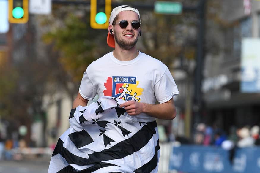 Man with sunglasses running in a marathon with the flag of Brittany